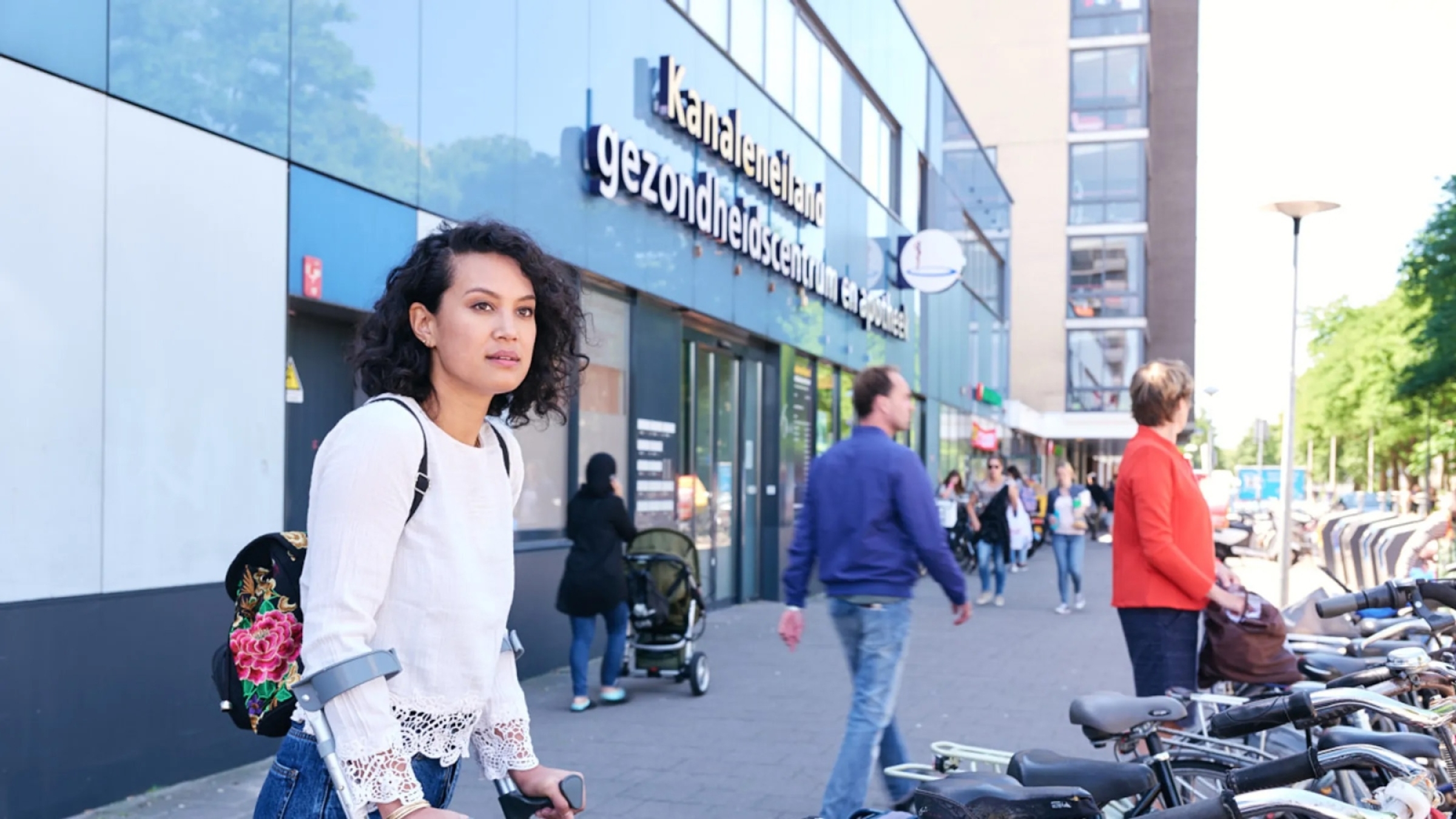Vrouw met krukken in winkelstraat.
